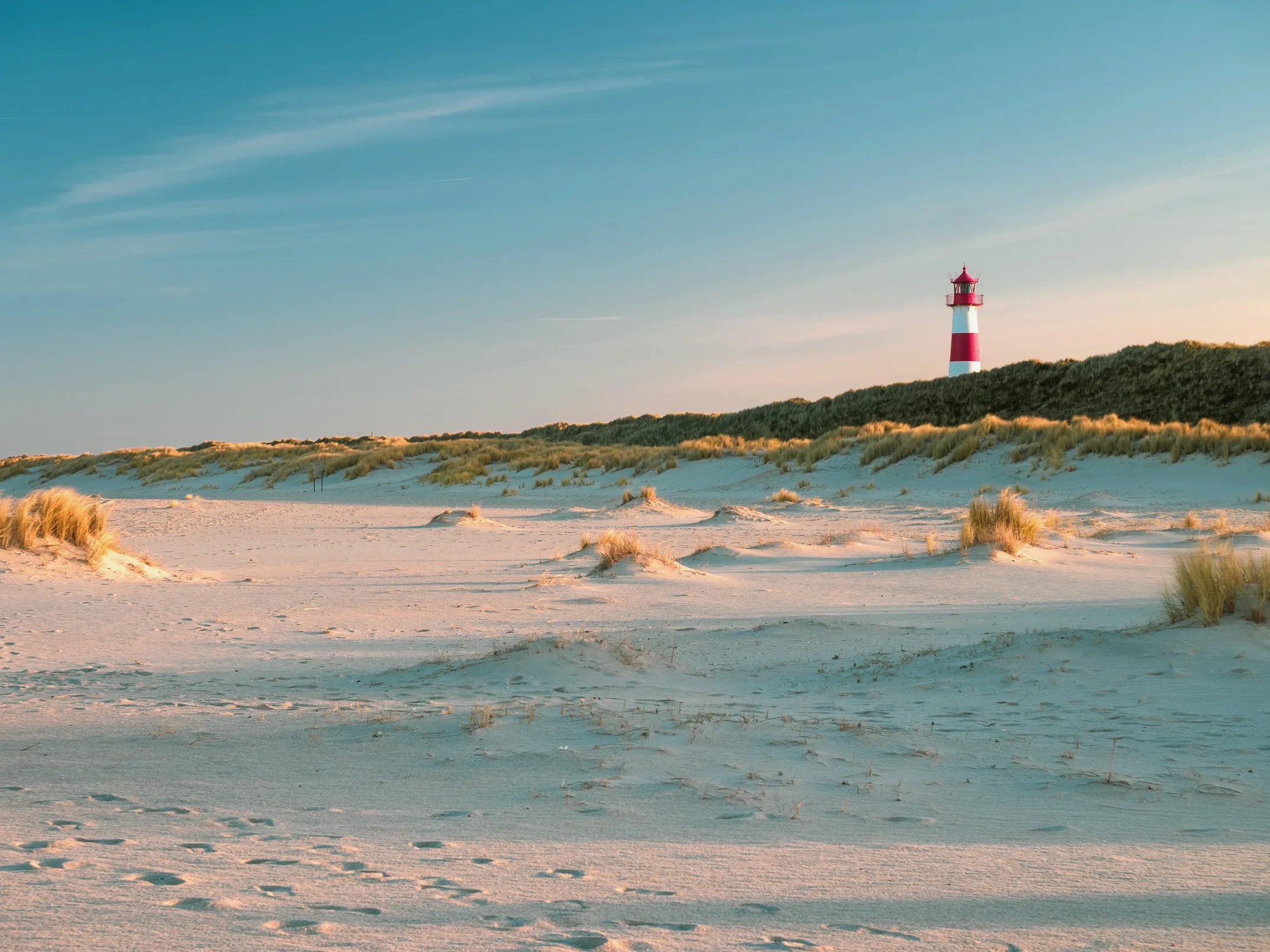 Dünenlandschaft mit dem rot-weißen Leuchtturm von Sylt